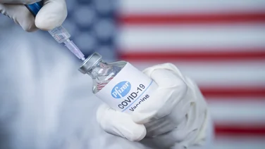 covid vaccine in front of usa flag