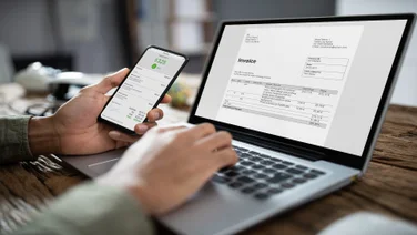 Businessman's Hands Working On Invoice On Laptop