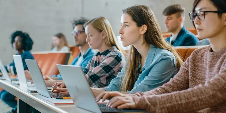 Students using laptops in college setting illustrating importance of tracking assets in schools and education