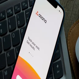 Asana app on a phone over a laptop