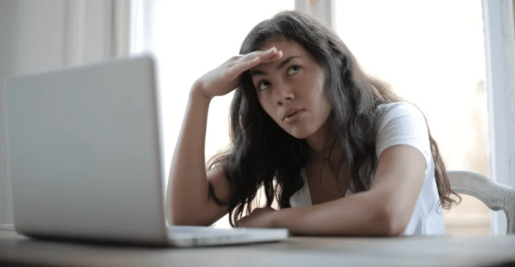 a woman looks annoyed in front of a laptop - women fared worse than men for online civility in 2021 according to microsoft