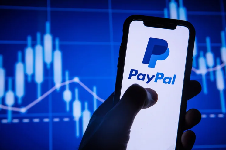 PayPal on phone screen in front of stocks