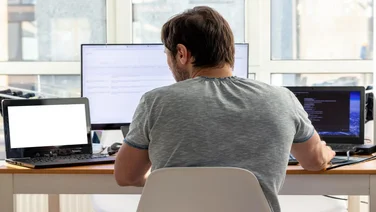 Man using three laptops