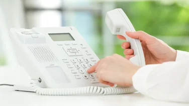 Person typing on desk phone numberpad