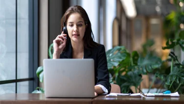 Woman enjoys some of the benefits of VoIP systems working on laptop