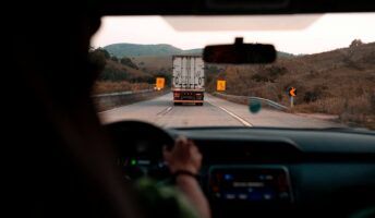 A truck as seen from the car behind it on the road.