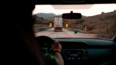 A truck as seen from the car behind it on the road.