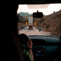 A truck as seen from the car behind it on the road.