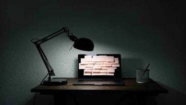 Desk with post it notes on computer screen (email overload)