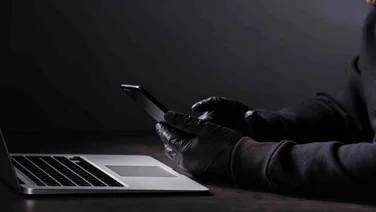 Hacker in gloves with phone