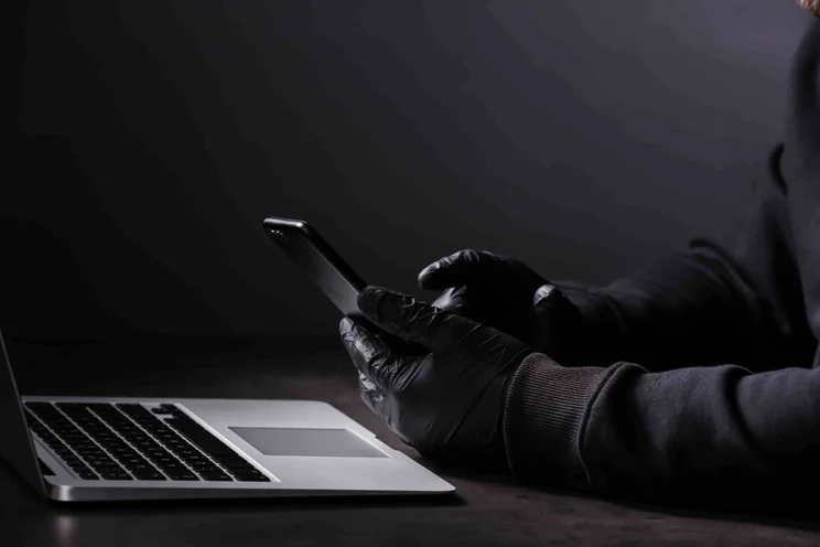 Hacker in gloves with phone