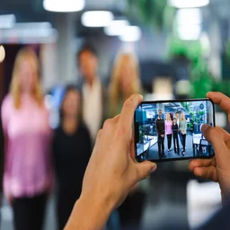 Person taking a picture of a group of people on their mobile. Source: Tech.co