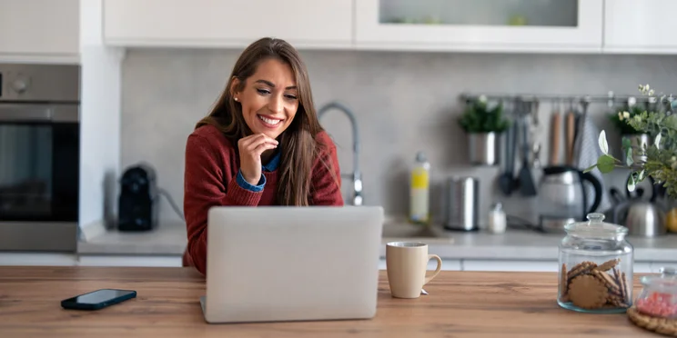 Businesswoman with hand on chin while having video call on laptop computer in home.