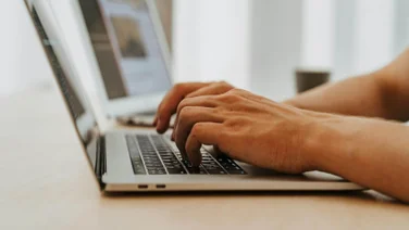 Hands typing on a Mac