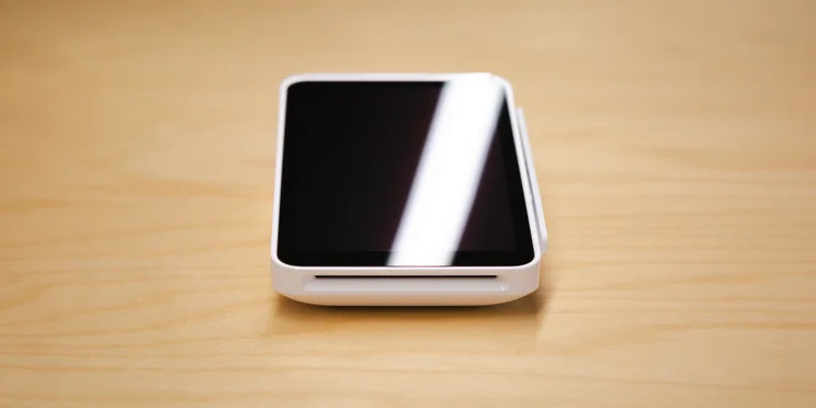 Square POS card reader and payment terminal on wooden table.