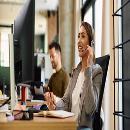 A woman sits at a desk using a conference call service.