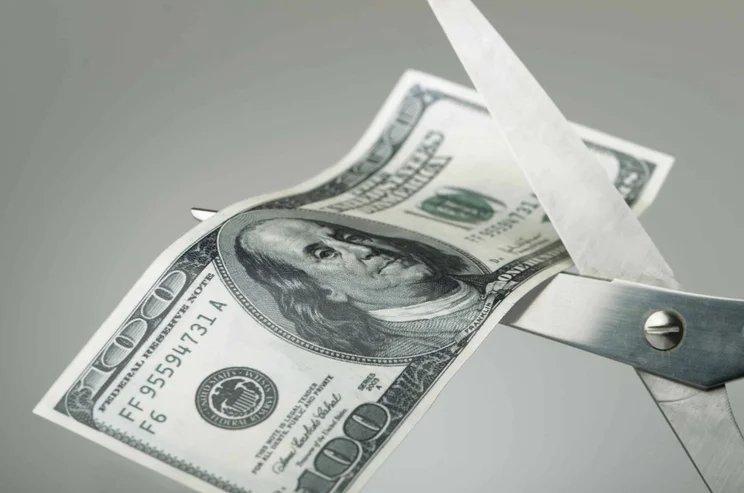 Scissors cutting money