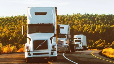 three trucks driving down a highway
