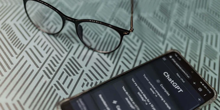 ChatGPT on a phone, near glasses.
