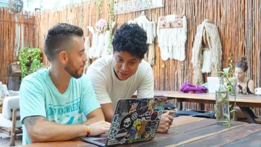 two remote workers in Mexico looking at laptop