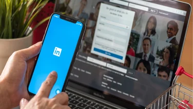 Person using LinkedIn on a mobile and laptop