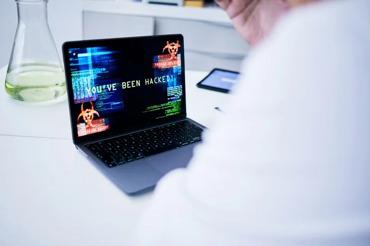 Man is white coat looking at a cyberattack on laptop