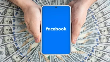 Facebook logo on blue screen in front of dollars