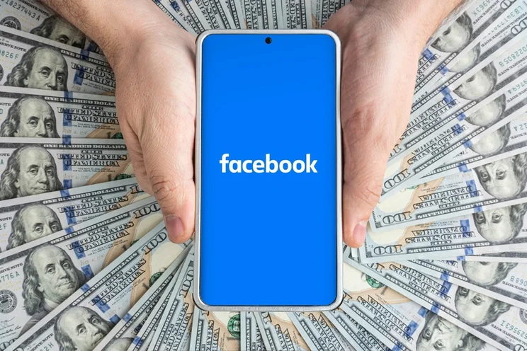 Facebook logo on blue screen in front of dollars