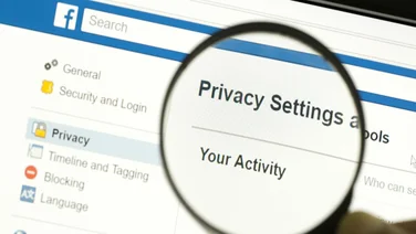 Hand holding a magnifying glass and magnifying the word "Privacy settings"