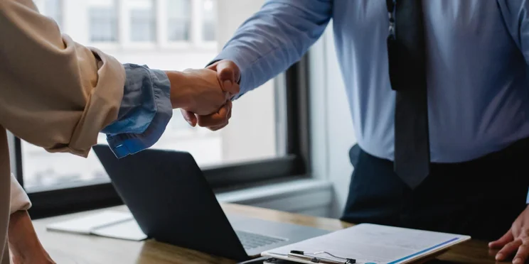 Office workers shake hands since one has paid leave.