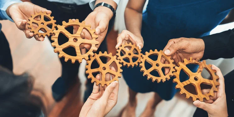 Office worker holding cog wheel as unity and teamwork in corporate workplace concept