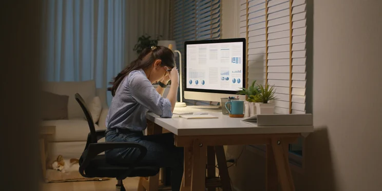 Young woman sitting head in hands at home office desk