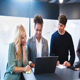 Three colleagues around a laptop. Source: Tech.co