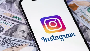 Instagram logo on iPhone against a background of dollars