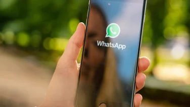 A woman holding and looking at her smartphone screen with as WhatsApp opens