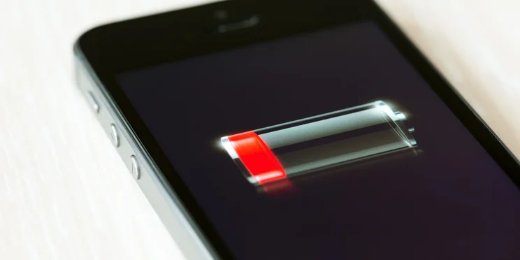 Apple iPhone with low battery symbol lying on desk