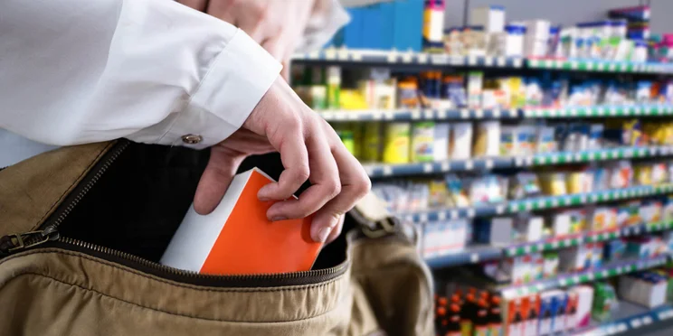 Shoplifter slipping item to steal into bag in store