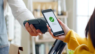 Customer using smartphone for digital NFC payment at restaurant