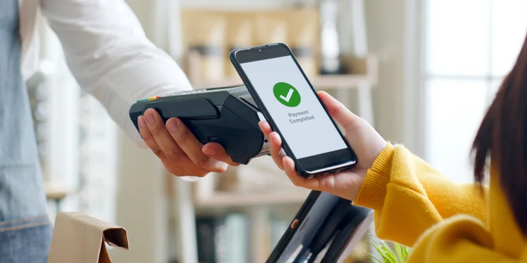 Customer using smartphone for digital NFC payment at restaurant