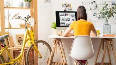 Woman works remotely at desk next to yellow bicycle