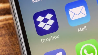 Dropbox logo close-up on an iPhone screen resting on wood table or bench
