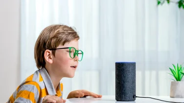 Child speaking to Amazon Echo Alexa-enabled smart speaker illustrating Alexa skills concept.
