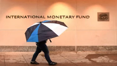 Man holding an umbrella outside of the IMF