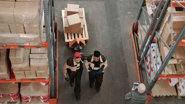 Two men haul a pallet of business assets.