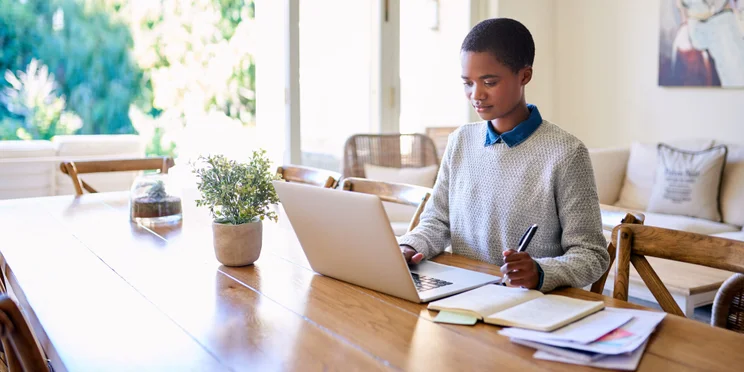 Young woman sits at home running online business from kitchen table