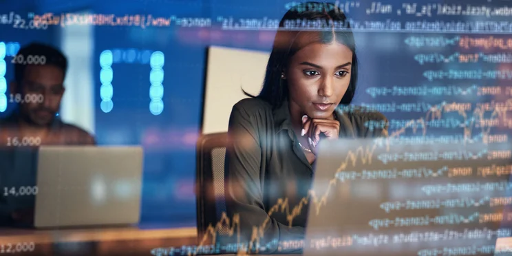 Woman sitting at laptop overlaid by data and code to illustrate IT and cybersecurity statistics