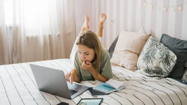 A remote worker on a laptop in her bed.