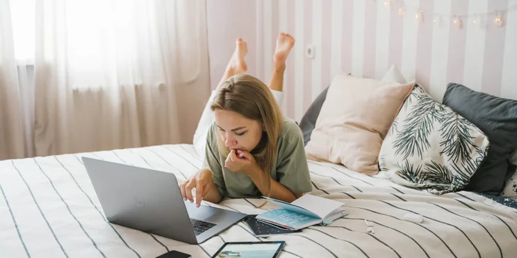 A remote worker on a laptop in her bed.