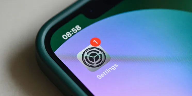 Apple Settings icon with notification on iPhone screen representing new iOS update