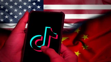 An America and Chinese flag in the background, with the TikTok app on a phone